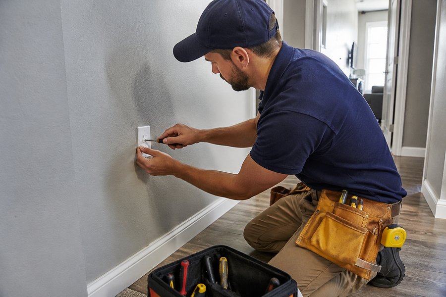 Técnico de handyman reparando un tomacorriente en el pasillo de una casa